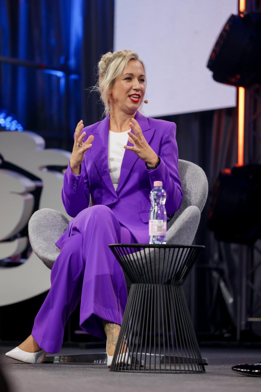 Denise Stadtegger bei einem Expertenpanel im violetten Anzug